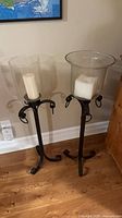 front view of both wrought iron floor candle holders with glass hurricanes and candles