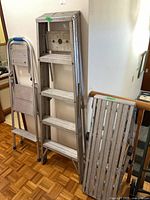 Three aluminum ladders leaning against railing