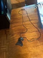 Full view of necklace laid on table showing pendant and cord