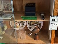 Shelf with coasters, Bluenose watch in box, separate wristwatch, shot glasses, decorative plate, wooden bird bottle opener