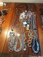 Overview of necklaces spread on table with bags of buttons