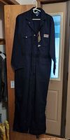 Full view of navy coverall hanging on hanger