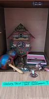 Cabinet view showing cuckoo clock, maracas, harmonica case, pen set