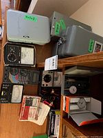 Lot overview showing meters, leads, Intermatic box, multiple grey enclosures