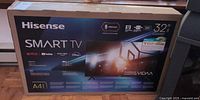 Front of sealed Hisense Smart TV box showing 32-inch size and streaming service logos