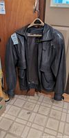 Full front view of grey leather jacket on hanger