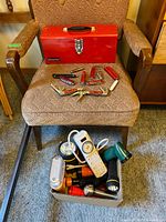 Overall lot: closed red toolbox on chair, multitools on seat, box of flashlights and power bar on floor