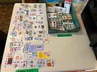 Tabletop view of all clipped stamps spread out beside green wooden tray containing additional stamps