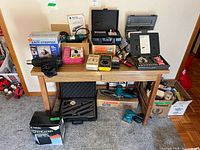 Overall lot view on table and floor, showing Makita tools, hot air gun, tester, accessories