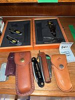 Overview of boxed Sheffield tools and assorted pocket knives on shelf