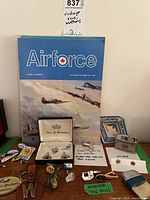 Overview of all items laid out including magazine, boxed cufflinks, lighters, pins and key holders