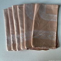 Six folded rose-blush linen napkins stacked showing colour and hem