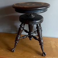 Full view of wooden adjustable piano stool showing seat, legs and stretcher