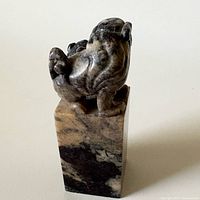 Front view of carved stone seal showing lion and pup on marbled base