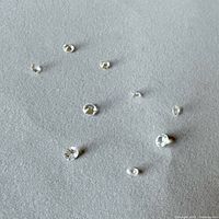 Eight loose round faceted white sapphires on foam background