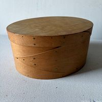 Side view of closed oval bentwood box showing swallow-tail joints and metal tacks