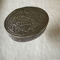Closed oval silver box showing engraved lid