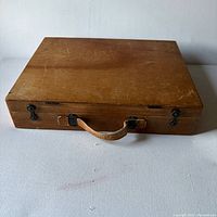 Closed wooden paint box showing exterior wear and handle