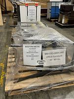 Stacked set of four light green armless office chairs, shrink-wrapped on pallet