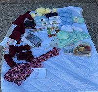 Overall view of yarns, needles, books, hoop on white backdrop