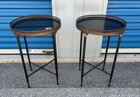 Front view of both round metal tables showing size, design and condition