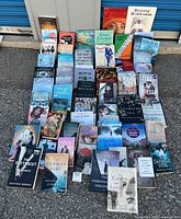 Group shot showing approximately 40 assorted paperback books laid out