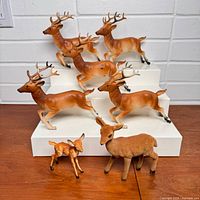 Seven reindeer figurines displayed on white risers