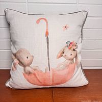 Front view of square pillow showing full bunny and umbrella illustration