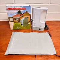 Boxed outdoor retractable clothesline, Steam Away steamer, storage bag on tabletop