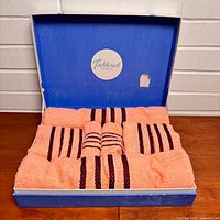 Open Fieldcrest box showing six peach towels with burgundy stripes