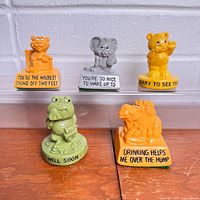 Group shot of all five Russ Greetings mini statues with visible slogans