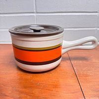 Stoneware pot with lid assembled, showing exterior stripes and handle