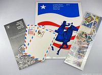 Front view of folder, sealed stamp strip, envelopes, order list pamphlet