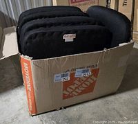 Box containing six black chair seat cushions