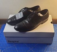 Oblique view of both shoes on box showing uppers and tag