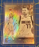 Front of holographic Luka Doncic Essentials rookie card in plastic sleeve