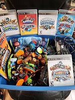 PS3 game cases, figures and portals inside blue bin