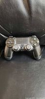Front view of black Sony DualShock 4 controller on black leather surface