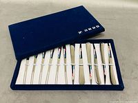 Open presentation box showing all 12 butter spreaders in fitted slots