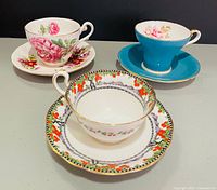 Three teacup and saucer sets displayed