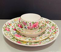 Stacked dinner plate, salad plate, saucer, and teacup showing pattern and gilt trim