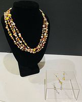 Necklace displayed on bust with earrings foreground