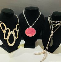 Three necklaces on busts showing overall designs and relative sizes