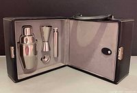 open case showing shaker, jigger, tube, stirrer cap inside fitted interior