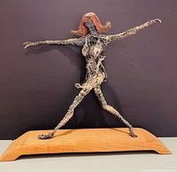 Full view of wire female sculpture on wooden base showing pose and scale