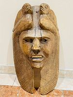 Front view of full carved wooden mask showing overall form and headdress