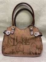 Front view of Ralph Lauren brown monogram handbag showing overall design, leather handles, flap strap accents