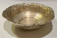 Angled view of entire silver-tone bowl showing floral rim and depth