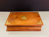 Closed wooden box showing brass inlays on lid