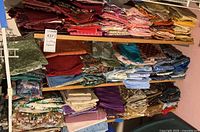 Three shelves filled with folded quilting fabric stacks sorted by color